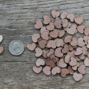 Puede incluir: Una colecci&oacute;n de peque&ntilde;os recortes de madera en forma de coraz&oacute;n en varios tonos de marr&oacute;n y un coraz&oacute;n blanquecino. Se incluye una moneda como referencia de tama&ntilde;o. Los corazones est&aacute;n esparcidos sobre una superficie de madera envejecida.