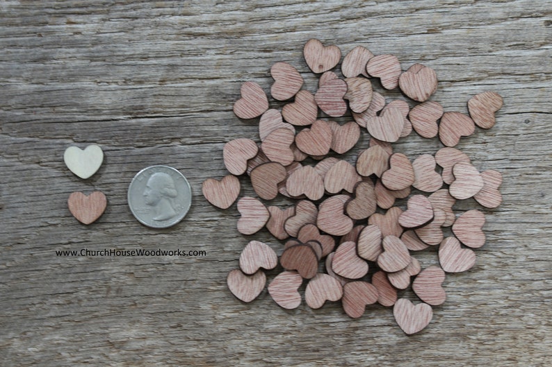Puede incluir: Una colecci&oacute;n de peque&ntilde;os recortes de madera en forma de coraz&oacute;n en varios tonos de marr&oacute;n y un coraz&oacute;n blanquecino. Se incluye una moneda como referencia de tama&ntilde;o. Los corazones est&aacute;n esparcidos sobre una superficie de madera envejecida.