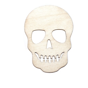 Pode incluir: Recorte de caveira de madeira com &oacute;rbitas oculares, cavidade nasal e fileira de dentes. A caveira &eacute; feita de madeira clara e provavelmente se destina a decora&ccedil;&otilde;es de Halloween ou Dia dos Mortos.