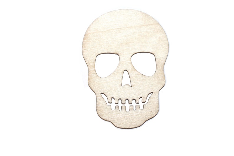 Pode incluir: Recorte de caveira de madeira com &oacute;rbitas oculares, cavidade nasal e fileira de dentes. A caveira &eacute; feita de madeira clara e provavelmente se destina a decora&ccedil;&otilde;es de Halloween ou Dia dos Mortos.