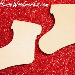 May include: Two unfinished wooden Christmas stocking ornaments on a red glitter background.  The stockings are blank and ready to be painted or decorated.