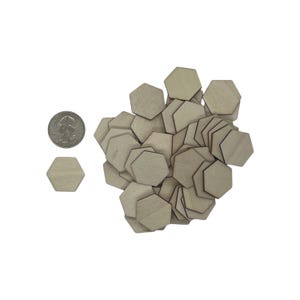 May include: A pile of unfinished wooden hexagon shapes, some are stacked on top of each other. The hexagons are about the size of a US quarter.