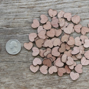 Puede incluir: Una colecci&oacute;n de peque&ntilde;os recortes de madera en forma de coraz&oacute;n de varios tama&ntilde;os, esparcidos sobre una superficie de madera envejecida. Se incluye una moneda para comparar el tama&ntilde;o. Los corazones son de color marr&oacute;n claro.