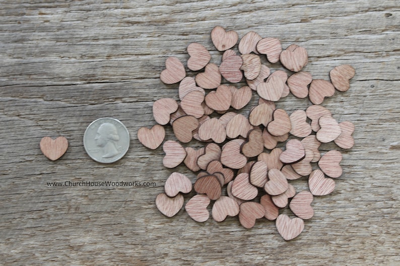 Puede incluir: Una colecci&oacute;n de peque&ntilde;os recortes de madera en forma de coraz&oacute;n de varios tama&ntilde;os, esparcidos sobre una superficie de madera envejecida. Se incluye una moneda para comparar el tama&ntilde;o. Los corazones son de color marr&oacute;n claro.