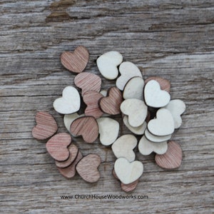 Puede incluir: Un conjunto de peque&ntilde;os corazones de madera en tonos marrones y crema. Los corazones est&aacute;n dispersos sobre una superficie de madera envejecida, creando una est&eacute;tica r&uacute;stica y encantadora. La imagen est&aacute; bien iluminada, resaltando la veta natural de la madera.