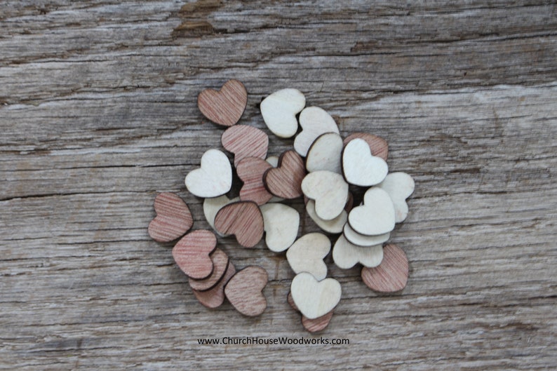 Puede incluir: Un conjunto de peque&ntilde;os corazones de madera en tonos marrones y crema. Los corazones est&aacute;n dispersos sobre una superficie de madera envejecida, creando una est&eacute;tica r&uacute;stica y encantadora. La imagen est&aacute; bien iluminada, resaltando la veta natural de la madera.