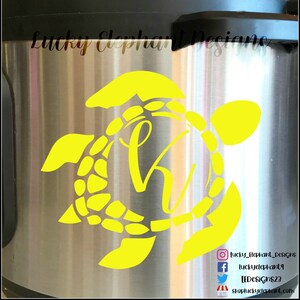 Puede incluir: Calcomanía de vinilo amarilla de una tortuga con un círculo en el centro. El círculo tiene una letra estilizada "H" en su interior. La calcomanía está sobre una superficie de acero inoxidable. El texto "Lucky Elephant Designs" es visible en la parte inferior de la imagen.