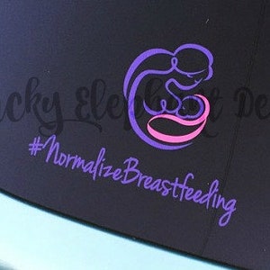Può includere: Un adesivo viola e rosa sul finestrino di un'auto con il testo "lucky elephant designs #normalizebreastfeeding".