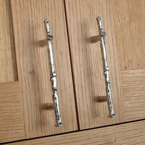 May include: Two silver cabinet pulls shaped like a branch with a rough, textured surface.