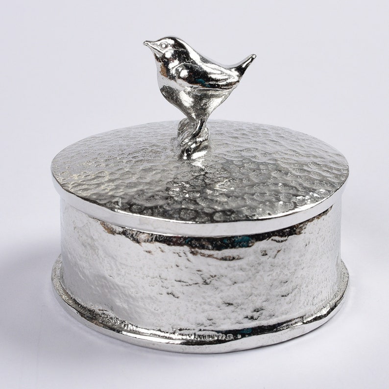 A round pewter box with a textured lid. On the lid is a three dimensional sculpted wren bird. The underside of the lid can be engraved with a personalised  message. A perfect 10th (tin) anniversary gift. Our pewter is 95% tin.