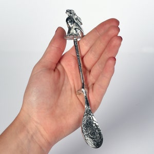 May include: A silver spoon with a hammered finish and a rabbit figurine on the handle.