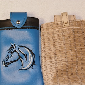 May include: Two small bags, one blue with a black horse design and the other brown with a textured fabric.