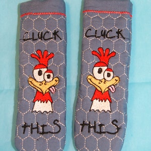Peut inclure: Une paire de maniques en tissu bleu avec un motif de poulet et le texte "CLICK THIS" brodé dessus.