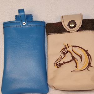 May include: Two phone pouches, one blue and one beige with a brown horse head embroidery.