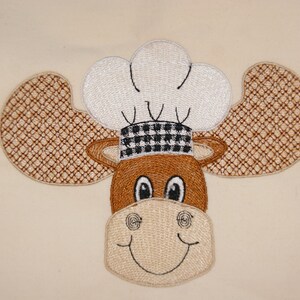 May include: Embroidered brown moose with white chef's hat and black and white checkered band. The moose has a smiling face with brown eyes.
