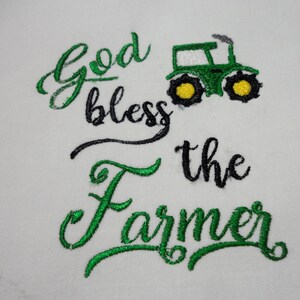 May include: Green embroidered design on a white background with the text "God bless the farmer" and a green tractor with yellow wheels.