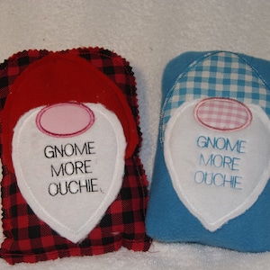 May include: Two plush gnome-shaped pillows with embroidered faces and the text "Gnome More Ouchie". One pillow is red with black and white plaid fabric and the other is blue with white and blue gingham fabric.