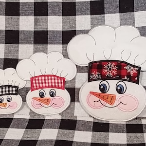 Puede incluir: Tres adornos de muñeco de nieve de fieltro blanco con sombreros de cuadros rojos y negros. El muñeco de nieve más grande tiene un sombrero de cuadros rojos y blancos con copos de nieve, el muñeco de nieve del medio tiene un sombrero de cuadros rojos y blancos, y el muñeco de nieve más pequeño tiene un sombrero de cuadros negros y blancos.