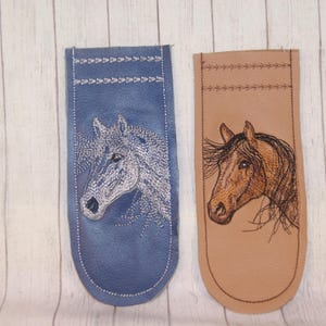 May include: Two leather bookmarks with embroidered horse head designs. One bookmark is blue with a white horse head, the other is brown with a brown horse head.