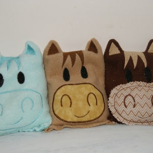 以下が含まれることがあります： 馬の形をしたぬいぐるみ枕が3つあります。1つは薄い青色、1つは茶色、1つは茶色のヘリンボーン柄のベージュです。