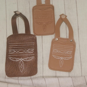 May include: Three leather pouches in varying shades of brown, each with a handle and decorative white stitching. The pouches feature a rectangular shape with a flap and a detailed design, suitable for carrying small items.