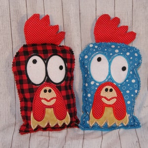 May include: Two plush toy roosters with large eyes. One rooster is red and black plaid with a red comb and wattle. The other rooster is blue with white polka dots and a red comb and wattle.