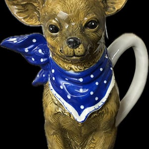 Könnte beinhalten: Eine Chihuahua-Teekanne aus Keramik mit braunem und beigem Fell, die ein blaues Halstuch mit weißen Punkten trägt. Auf dem Kopf sitzt eine kleine weiße Tasse. Die Teekanne hat einen weißen Griff und Ausguss.