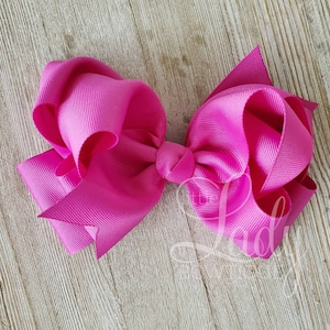 May include: A large, bright pink hair bow made from grosgrain ribbon. The bow is tied in a classic style with a center knot.