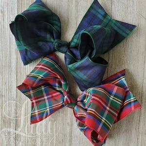 May include: Two large plaid hair bows. One bow is green and blue plaid, the other is red and green plaid.