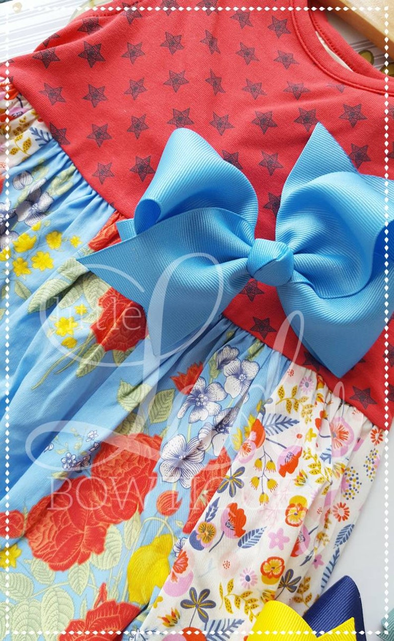 May include: A blue and white floral print dress with a red star print top and a large blue bow.