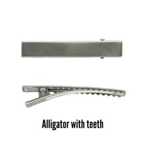 May include: Two silver-colored alligator hair clips. One clip is shown from the top, and the other is shown from the side, revealing the teeth. The text "Alligator with teeth" is below the clips.