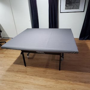 Puede incluir: Una mesa plegable gris con patas negras y ruedas. La mesa est&aacute; en una habitaci&oacute;n con suelo de madera y paredes blancas. La mesa tiene una etiqueta que dice "&iexcl;Para los campeones que hay en ti!"
