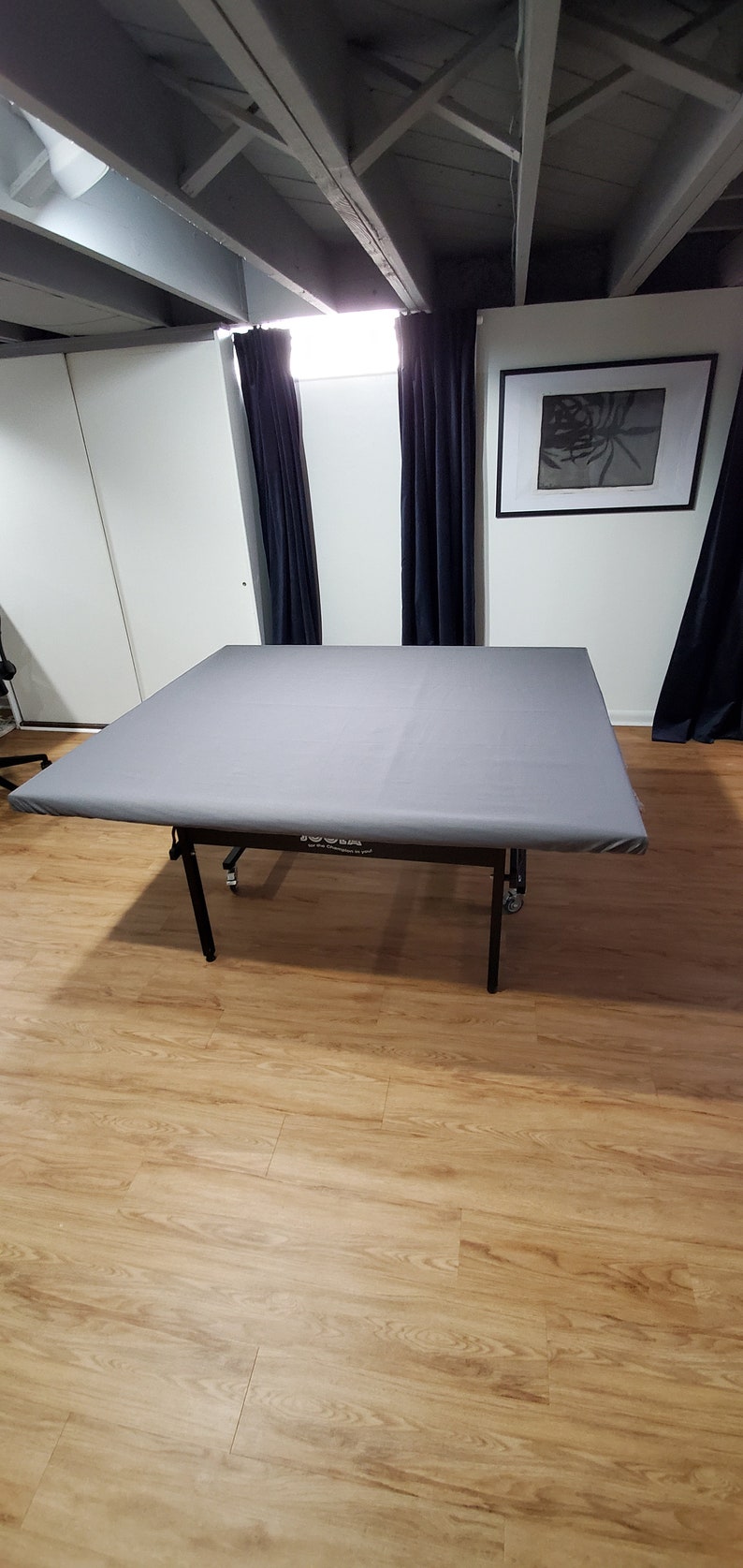 Puede incluir: Una mesa plegable gris con patas negras y ruedas. La mesa est&aacute; en una habitaci&oacute;n con suelo de madera y paredes blancas. La mesa tiene una etiqueta que dice "&iexcl;Para los campeones que hay en ti!"