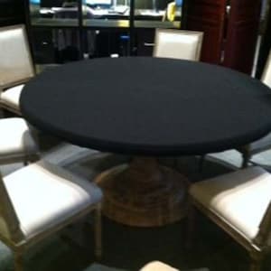 Puede incluir: Una mesa redonda con un mantel negro y seis sillas. Las sillas son de madera y tienen un asiento de tela blanca. La mesa est&aacute; en una habitaci&oacute;n con un suelo de madera oscura.