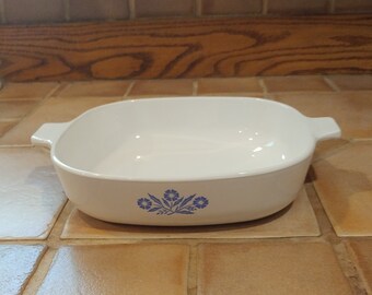 May include: White ceramic baking dish with blue floral design. The dish has two handles on the sides.