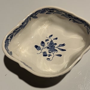 May include: A white ceramic bowl with a blue floral design. The bowl has a scalloped edge and is perfect for serving snacks or desserts.