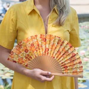FLOWER POWER: Bright yellow, orange and red 70s hippie retro floral print folding hand fan with natural wood ribs