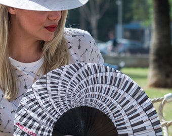 PLAY IT COOL: Black and white piano keyboard design with fuchsia color text folding hand fan with black wood ribs - perfect for music lovers