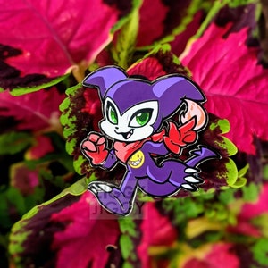 May include: Purple and red cartoon character with a yellow smiley face on its chest, running with its right arm raised. The character is a pin with a shiny finish.