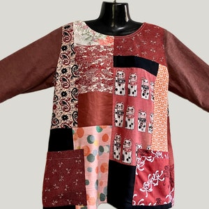 May include: A brown, 3/4 sleeve top with a patchwork design. The patches are made of different fabrics and feature various patterns, including cats, polka dots, and floral designs.