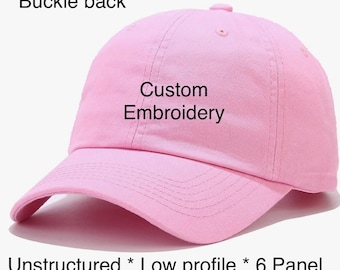 May include: A light pink baseball cap with the text "Custom Embroidery". The cap has a buckle back, unstructured design, low profile, and a 6-panel construction. This hat is a stylish accessory.