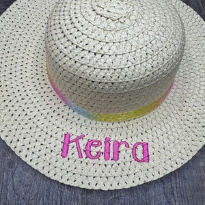 May include: A straw hat with a rainbow ribbon and the name "Keira" embroidered in pink.