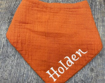 May include: A burnt orange bandana with the name "Holden" embroidered in white.