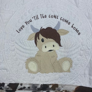 May include: White quilted fabric with a brown and white cow applique and the text "Love You 'til the cows come home".