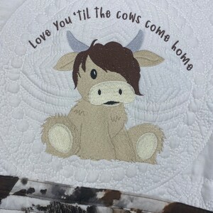May include: Embroidered white fabric with a brown and white cow design. The text "Love You 'til the cows come home" is stitched in brown thread.