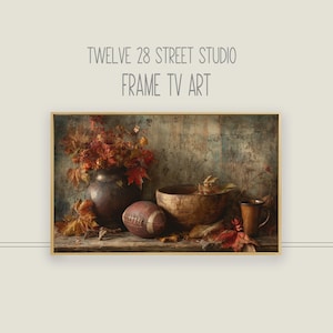 May include: A framed digital art print featuring a still life with a football, a vase of autumn leaves, a wooden bowl, and a mug. The artwork has a vintage aesthetic with warm, earthy tones. The text "TWELVE 28 STREET STUDIO FRAME TV ART" is at the top.