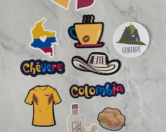 May include: A collection of eleven colorful stickers featuring a yellow, blue, and red heart cluster, a map of Colombia, a coffee cup, the Guatape rock, the words Chévere and Colombia, a hat, a yellow jersey, a bottle with a glass, and bread.