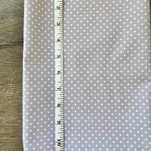 May include: A gray fabric with white polka dots. The fabric is measured with a ruler showing 11 inches.