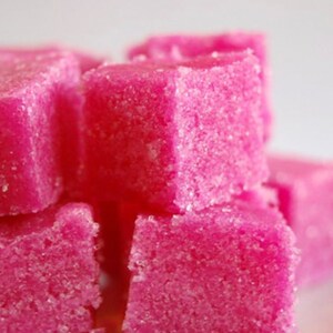 May include: Pink sugar cubes, a sweet treat, with a grainy texture.