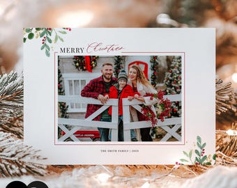 Puede incluir: Una tarjeta de felicitación navideña rectangular con una fotografía central de una familia de tres personas detrás de una valla blanca. La tarjeta tiene un borde blanco con detalles de acebo y bayas en acuarela, el texto Merry Christmas y THE SMITH FAMILY | 20XX.